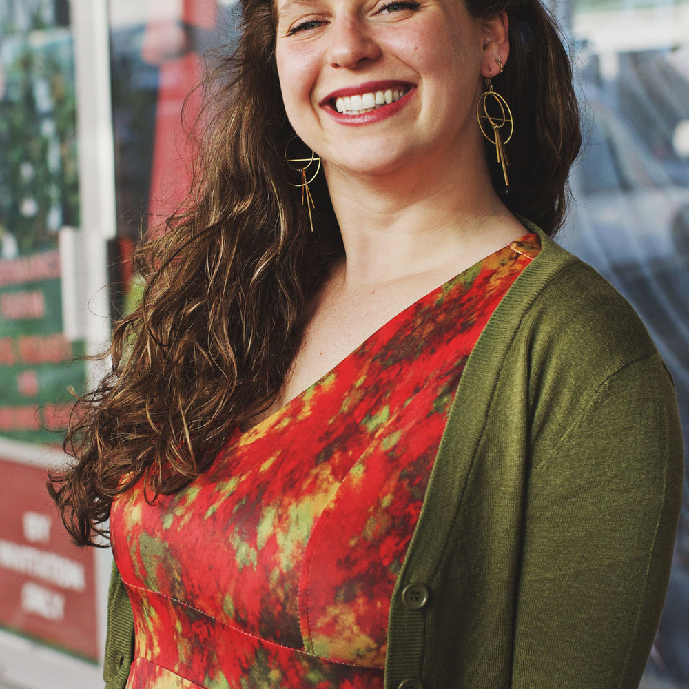 
                  
                    Woman wearing a colorful dress with a green cardigan in an urban setting
                  
                
