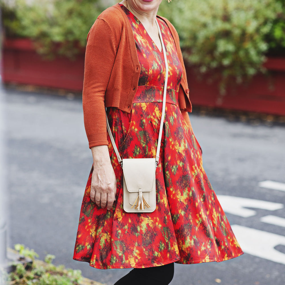 
                  
                    Woman wearing an autumn color abstract print dress with an orange cardigan walking outdoors
                  
                