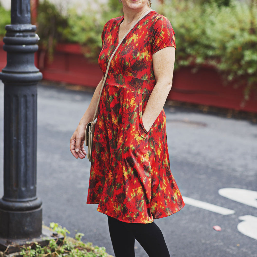 
                  
                    Woman wearing an autumn color abstract print dress with an orange cardigan on a city street.
                  
                