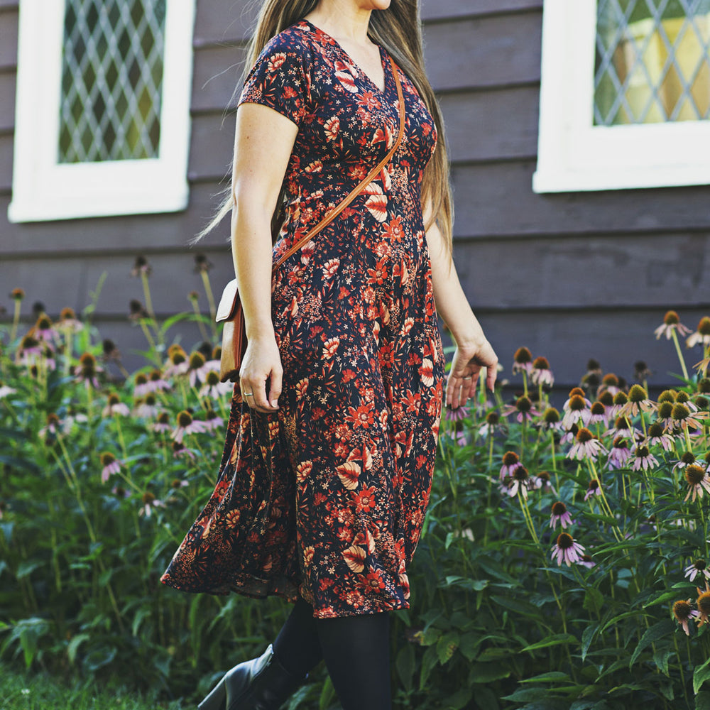 
                  
                    Woman in a floral dress walking outdoors near a garden
                  
                