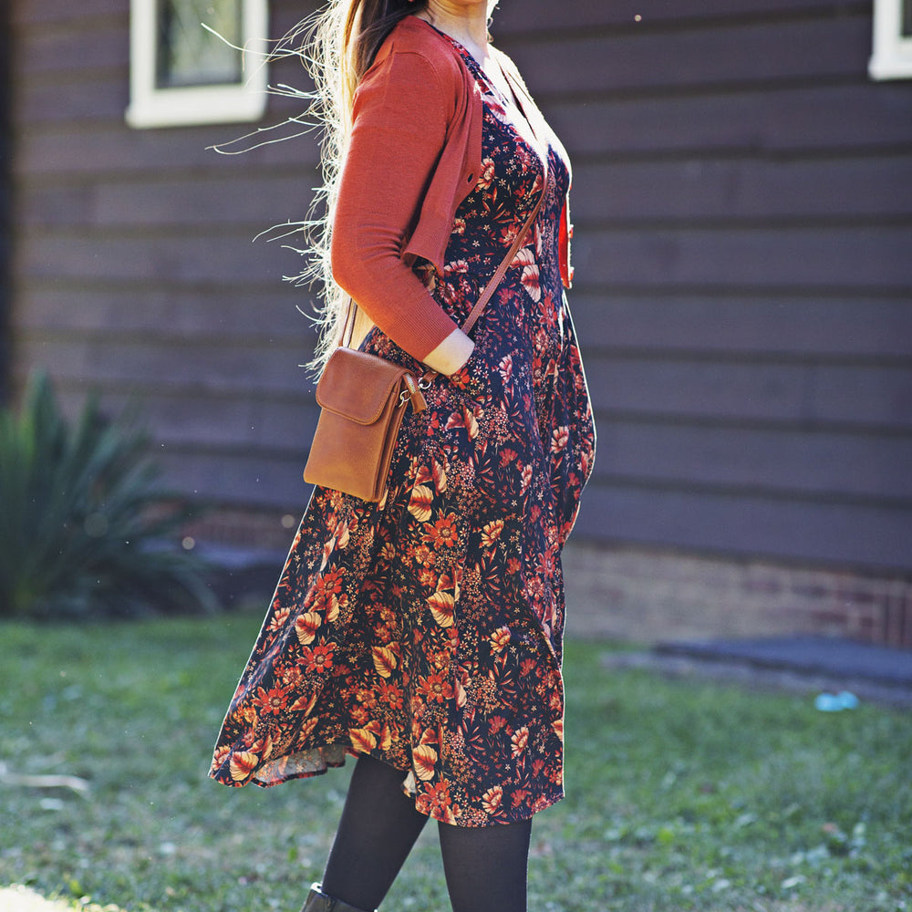 
                  
                    Woman wearing a floral dress and burnt orange cardigan standing outdoors.
                  
                