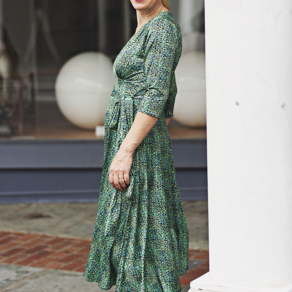 
                  
                    Woman wearing a green patterned dress standing outdoors.
                  
                